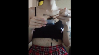 a lady with a tattoo in a top and a plaid skirt eats sushi