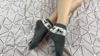 Slut with long legs caresses her feet in gray New Year socks with deer